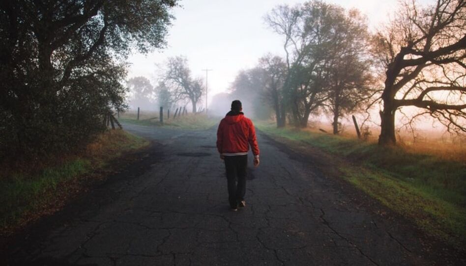 Homem caminhando em estrada com neblina que mostra coisa caminhos.