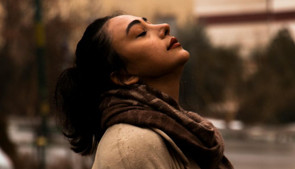 Mulher com os olhos fechados e cabeça apontada para o céu buscando confiar no Senhor.