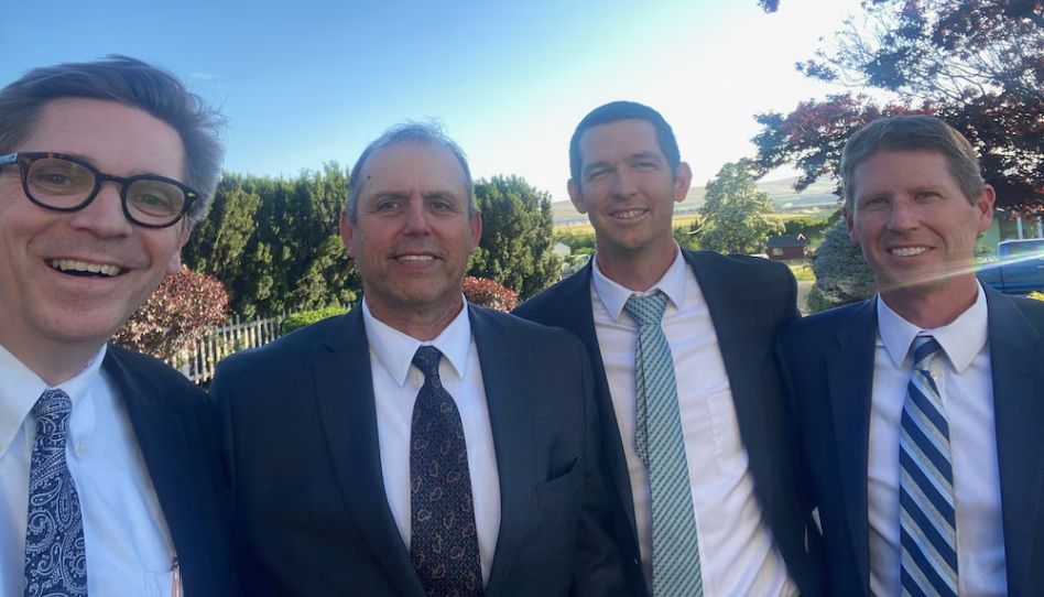 Os três primos tiram uma foto com um outro bispo da mesma estaca durante uma conferência.