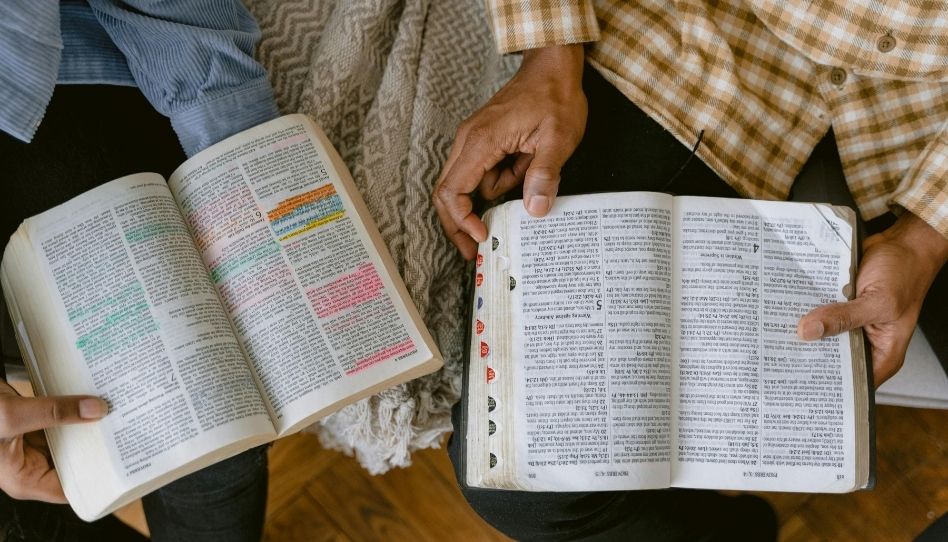 Duas pessoas sentadas juntas estudando a Bíblia e amor lendo sobre o amor incondicional de Deus.